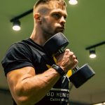 A man intensely lifting dumbbells indoors, showcasing strength and determination.